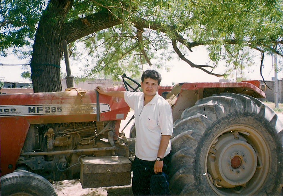 A young Mosa Rahimi standing beside a red tractor